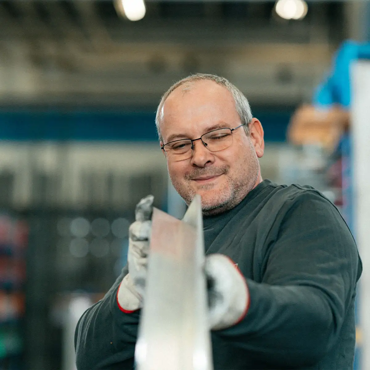 Arbeiter hält langes Winkelprofil in einer industriellen Umgebung.
